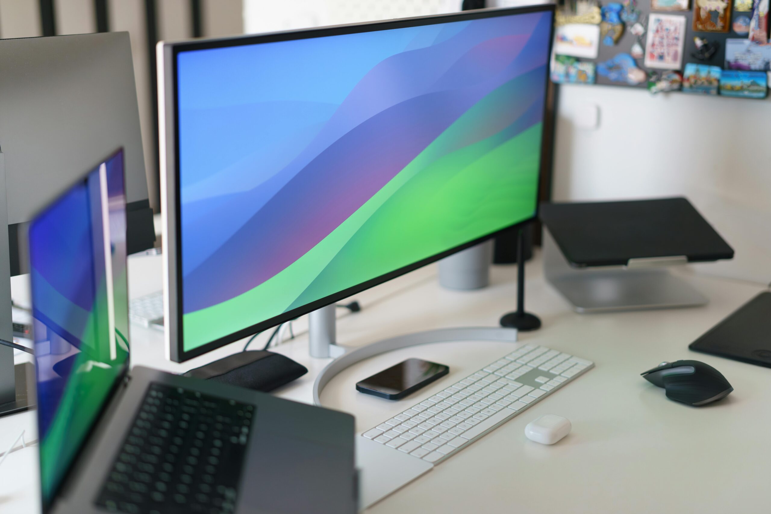 Sleek home office setup with multiple monitors, keyboard, smartphone, and stylish decor.